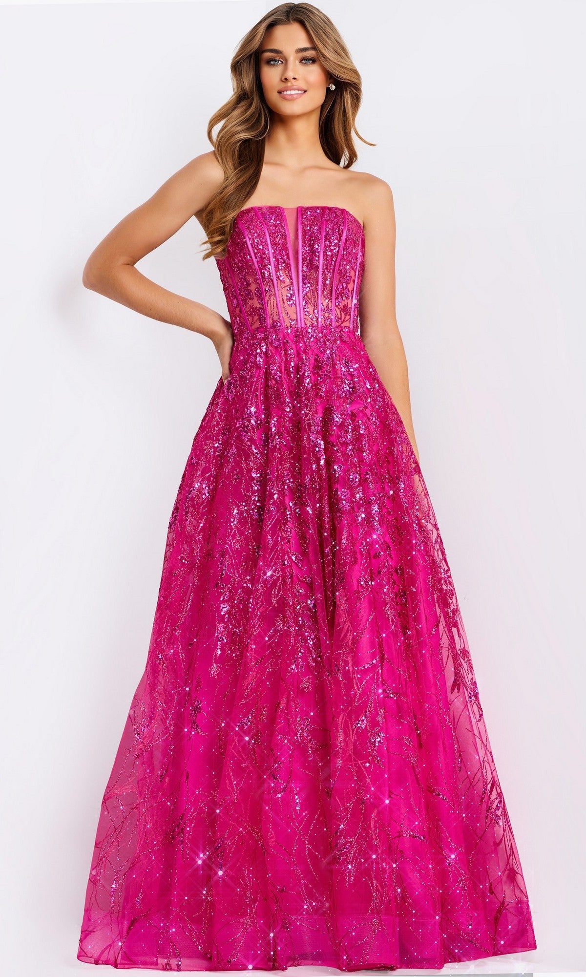A woman wearing the Jovani 45913 long prom dress in bright pink, with a strapless design, sheer corset bodice, and sparkling sequin embellishments on the floor-length skirt.